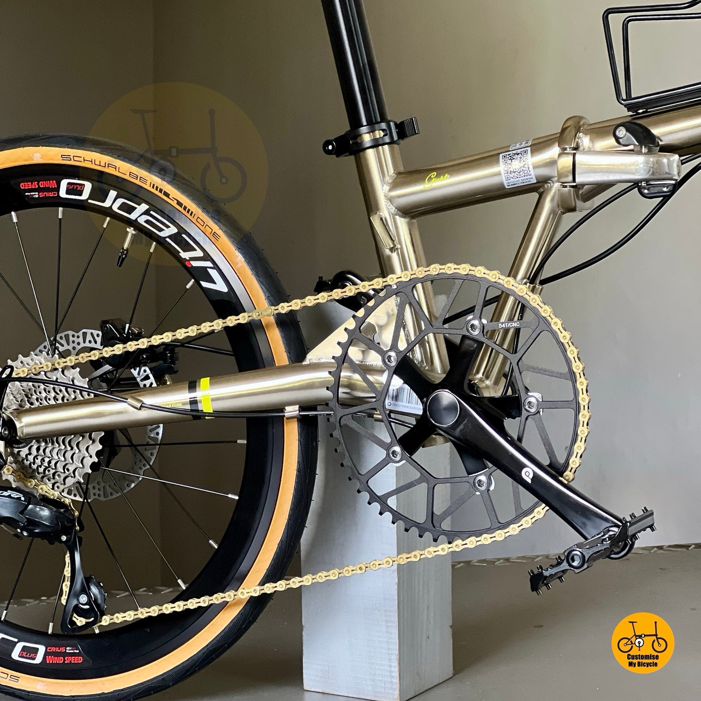 Angled view focusing on crankset and chainring of Fnhon Gust 22β titanium gold, showing polished metallic frame reflections.