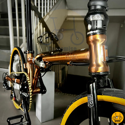 Folding bicycle with a stylish rose gold frame and brown leather saddle
