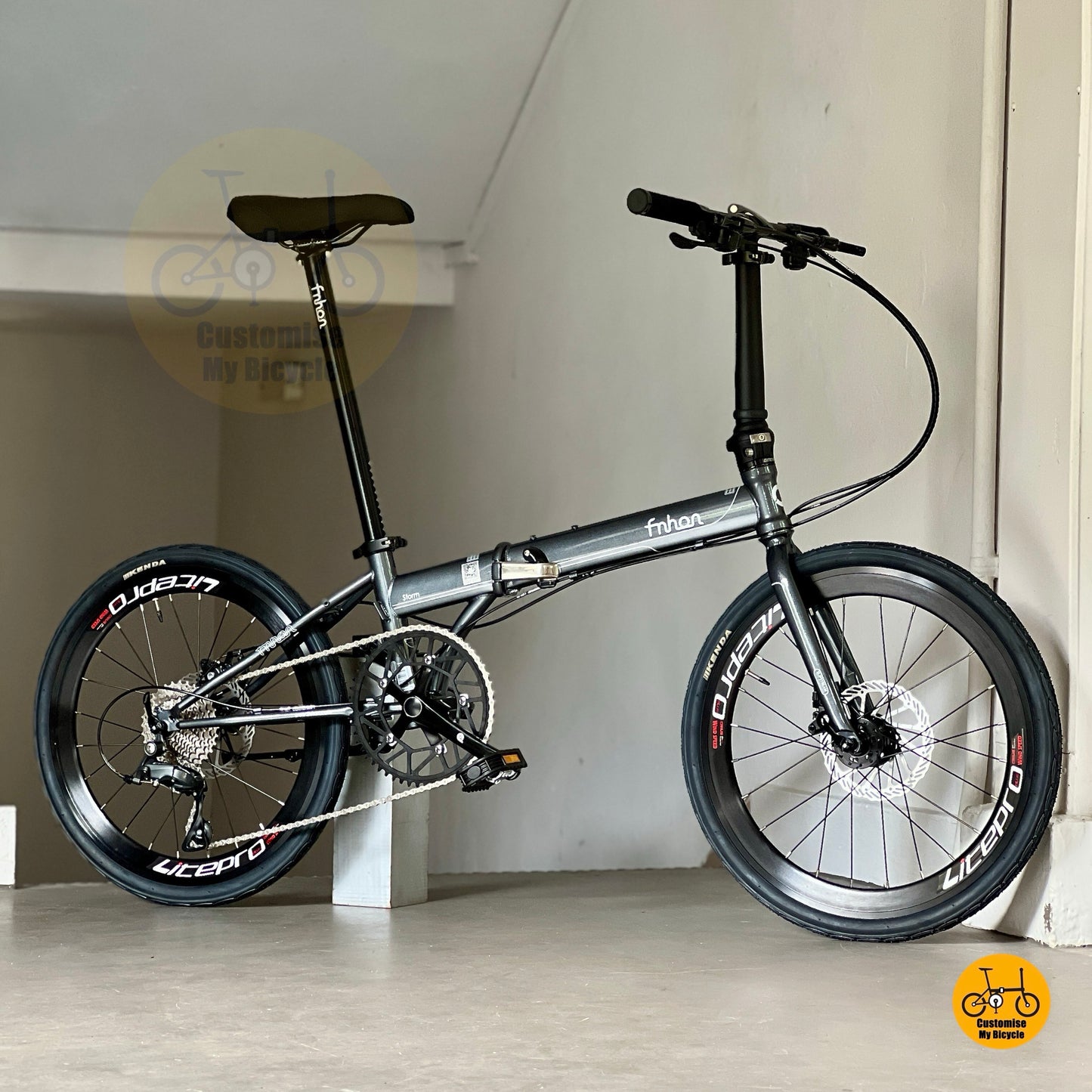 Folding bicycle with black frame and wheels on a light colour floor.